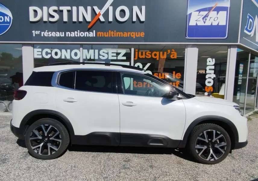 Profil côté gauche d'un Citroën C5 Aircross blanc nacré avec toit noir et jantes alliage bi-ton 19 pouces.
