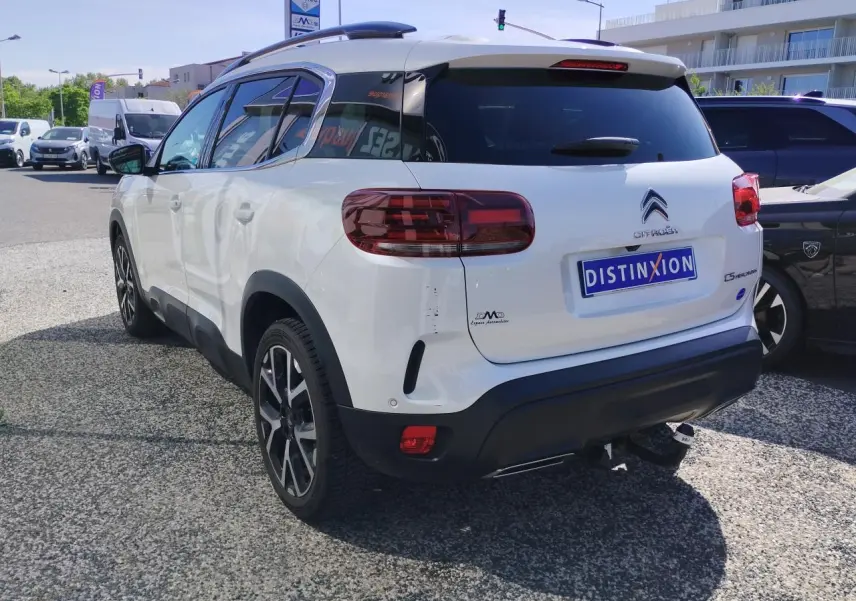 Vue 3/4 arrière droite d'un Citroën C5 Aircross blanc nacré avec toit noir et attelage col de cygne.