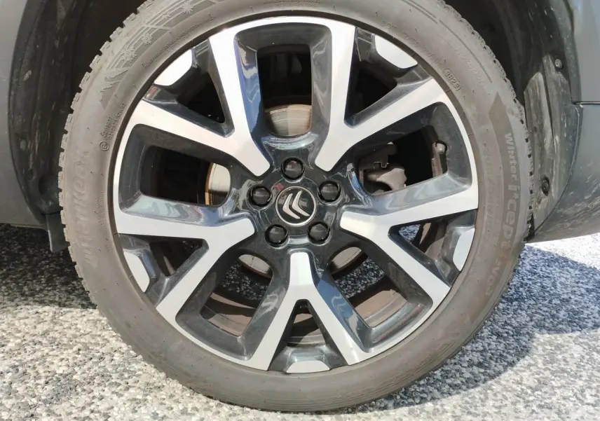 Gros plan sur la jante alliage bi-ton noir et argentée avec logo Citroën au centre du C5 Aircross blanc nacré.