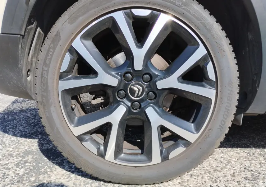 Gros plan sur la jante alliage bi-ton noire et argentée du Citroën C5 Aircross blanc nacré, roue avant droite.