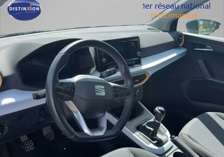 Vue intérieure du poste de conduite de la SEAT Arona 2025, volant multifonction et levier de vitesses manuelle visibles.