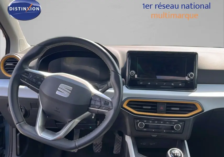 Intérieur du SEAT Arona 2025 vu de face, volant multifonction et écran tactile avec cadre décoratif bois clair.