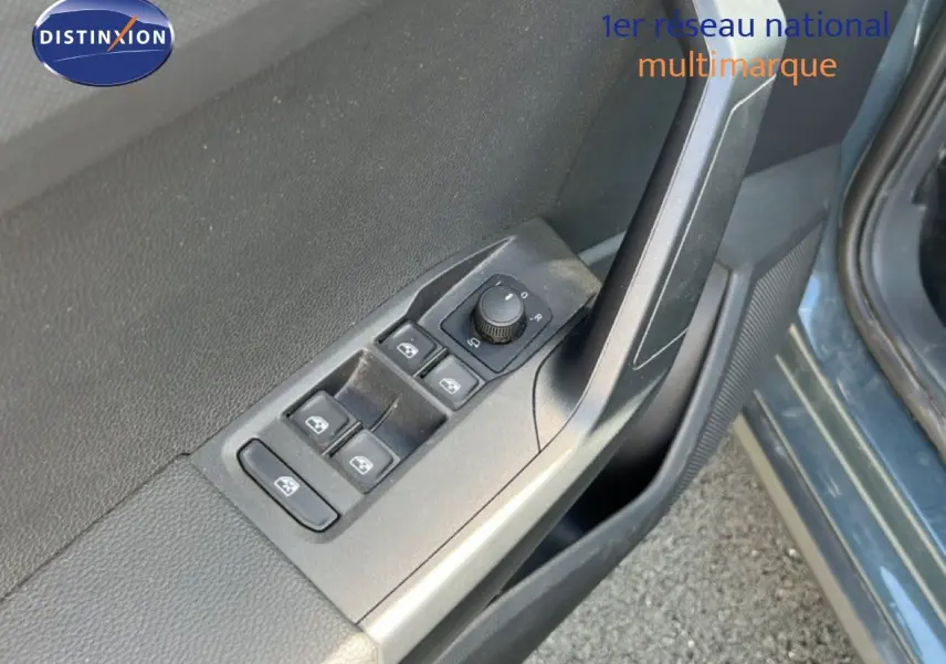 Gros plan sur les commandes des vitres et rétroviseurs côté conducteur d'un SEAT Arona bleu Fjord avec toit blanc.