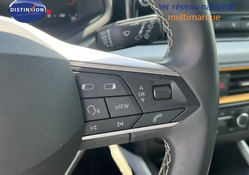 Gros plan sur le volant multifonction en cuir noir avec surpiqûres blanches du SEAT Arona 2025, intérieur gris-noir.