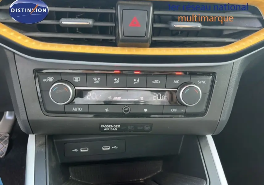 Gros plan sur la console centrale du SEAT Arona bleu Fjord, avec climatisation digitale et bordure jaune contrastante.