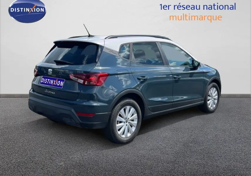 Vue 3/4 arrière droite d'un SEAT Arona bleu Fjord avec toit blanc, jantes 16 pouces et vitres teintées.
