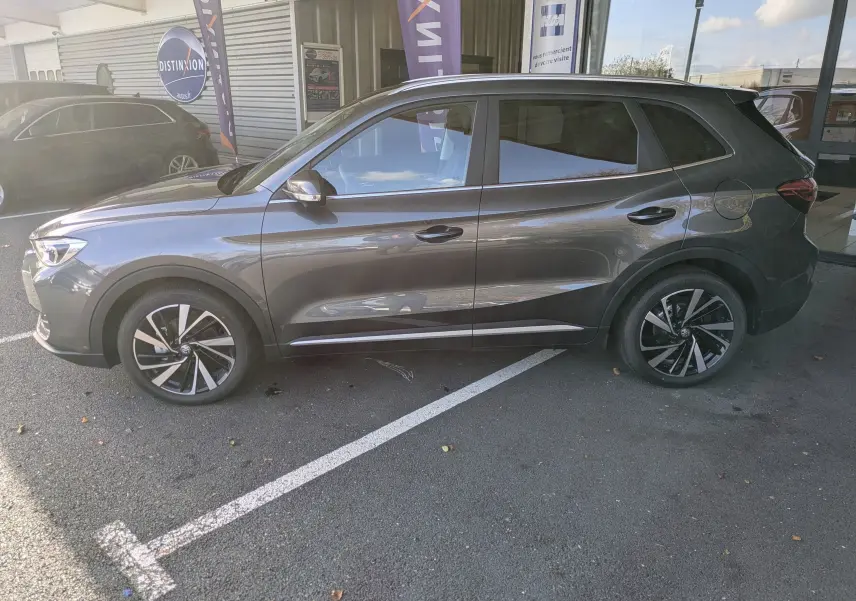 Vue 3/4 avant du MG ZS 2026 gris Candem avec jantes alliage 18 pouces et toit panoramique visible.