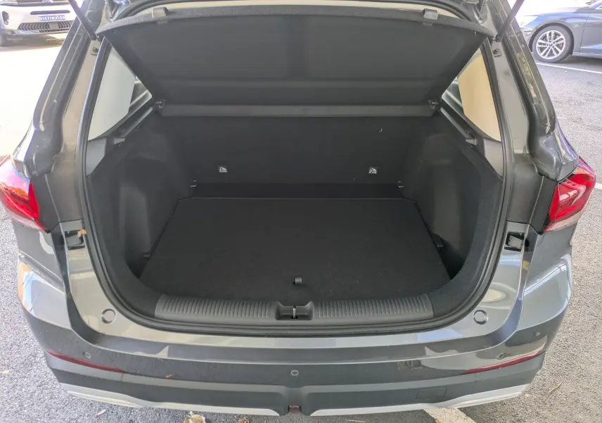 Coffre ouvert vu de l'arrière d'un MG MOTOR ZS 1.5 L Hybrid+ Candem Grey avec hayon et feux arrière LED visibles.