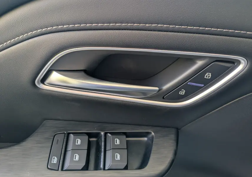 Vue intérieure côté gauche des sièges arrière en similicuir noir perforé du MG MOTOR ZS 1.5 L Hybrid+ 2026 avec porte ouverte.