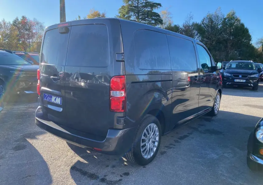 Vue 3/4 arrière droite d’un Peugeot Expert Fourgon gris titane avec vitres latérales opaques et jantes alliage.