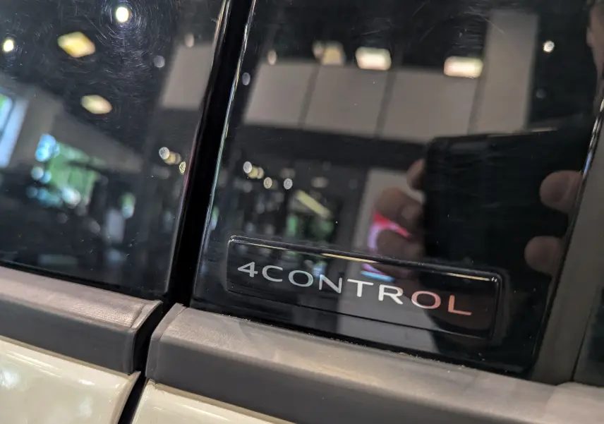 Gros plan sur l’inscription 4Control sur la partie noire entre les vitres d’un Renault Austral blanc nacré au toit noir.