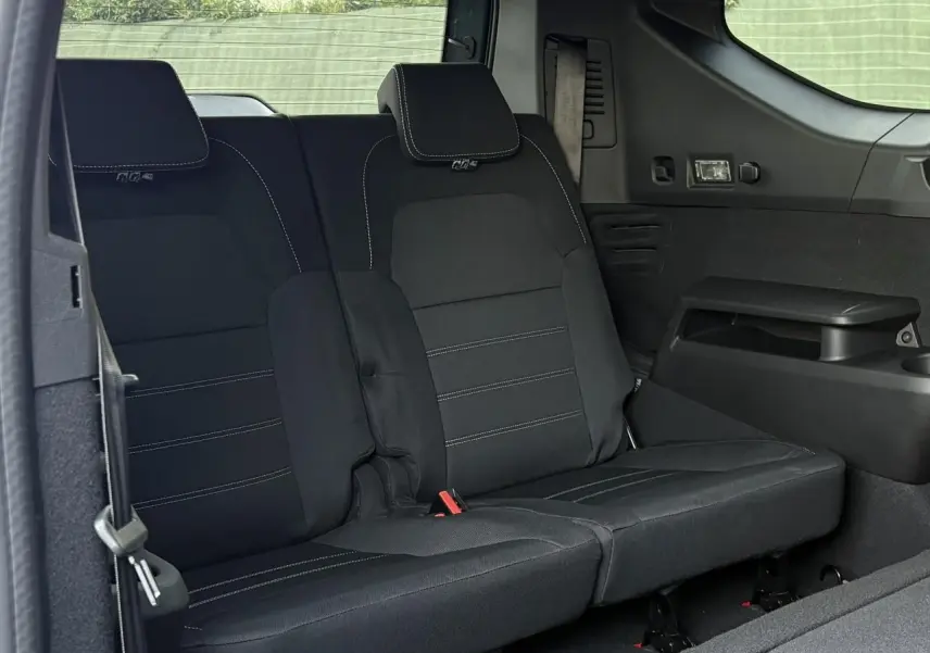 Banquette arrière rabattable noire du Dacia Jogger 2024 vue de côté droit, avec ceinture de sécurité et accoudoir intégré.