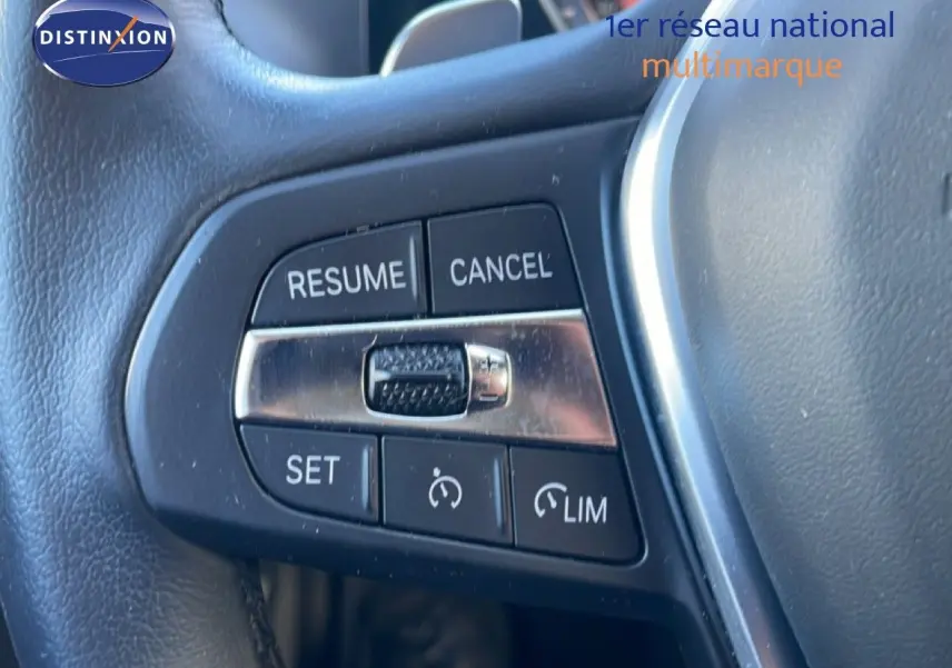 Gros plan sur les commandes de régulateur de vitesse au volant noir d’une BMW Série 3 Touring F31 316d 2022.