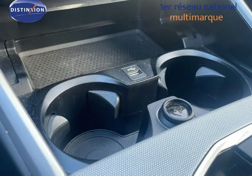 Gros plan sur les porte-gobelets et prise USB du compartiment central d’une BMW Série 3 Touring noire.