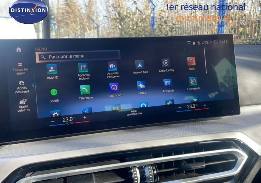 Écran tactile central affichant le menu multimédia et climatisation dans l'habitacle d'une BMW Série 3 Touring noire.