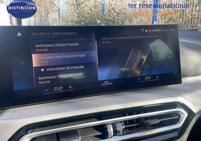 Écran central tactile de la BMW Série 3 Touring F31 noir, affichant les alertes de sécurité et la climatisation à 23°C.