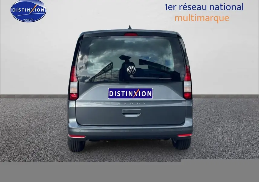 Vue arrière d'un Volkswagen Caddy gris indien 2025 avec vitres teintées et feux verticaux rouges.