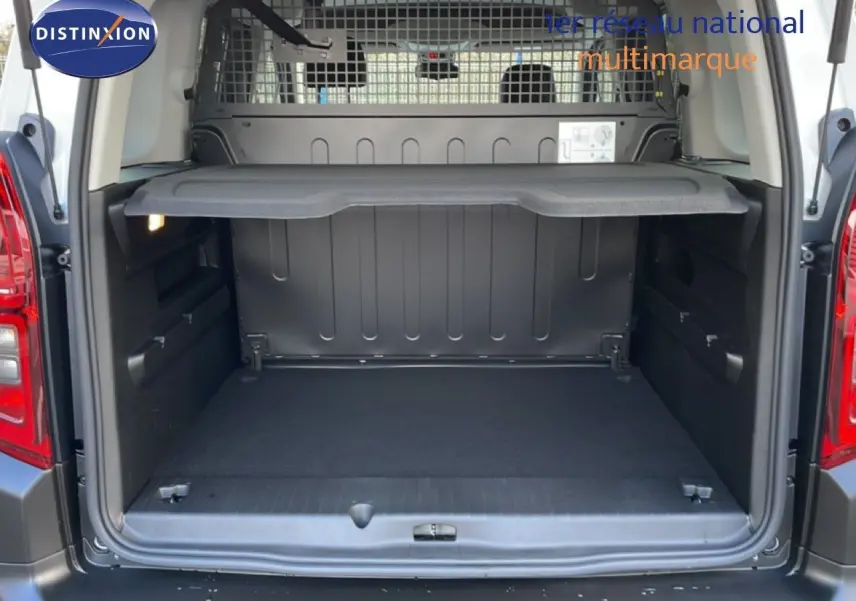 Vue arrière du coffre ouvert du Citroën Berlingo blanc glacier, montrant l'espace de chargement et la grille de séparation.