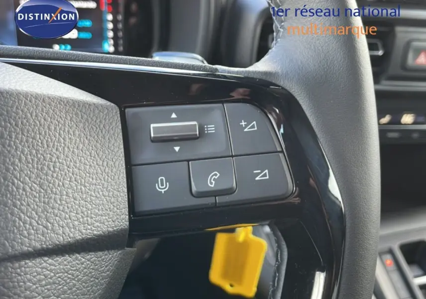 Gros plan sur les commandes multifonctions noires à gauche du volant cuir gris du Citroën Berlingo blanc glacier.