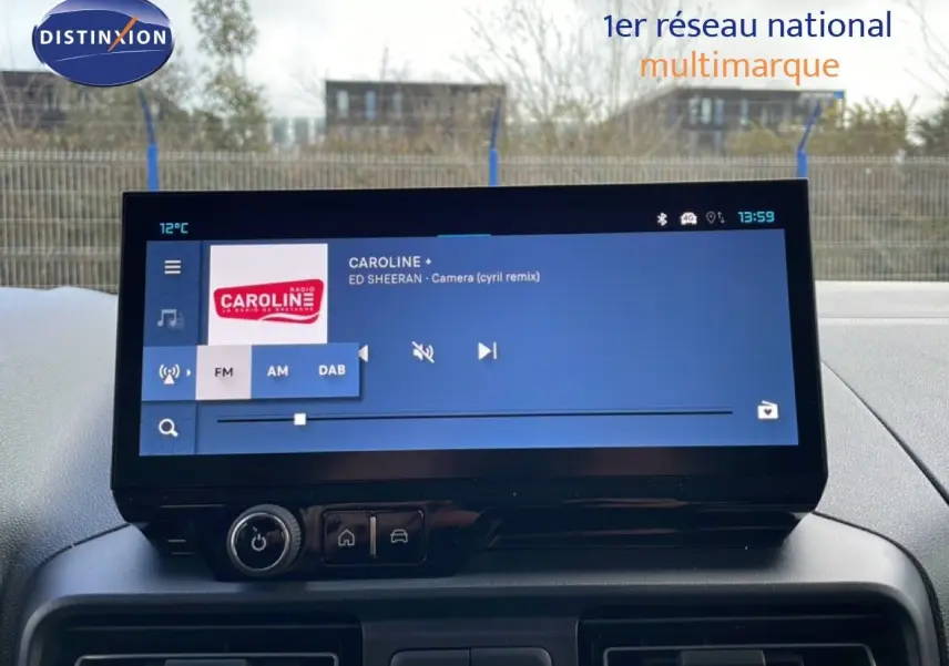 Écran tactile central du tableau de bord du Citroën Berlingo blanc glacier, affichant une radio FM en extérieur.