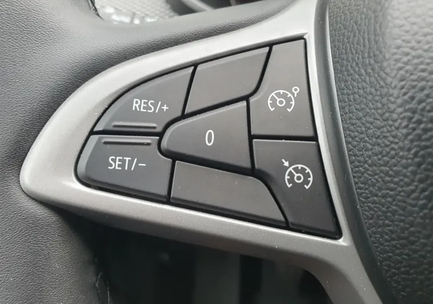 Gros plan sur les commandes du régulateur de vitesse au volant d’une Dacia Sandero 2025, intérieur noir.