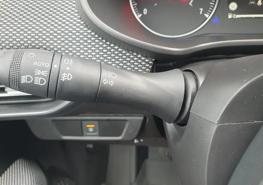 Gros plan sur la commande des feux et clignotants dans l’habitacle noir du Dacia Sandero 2025.