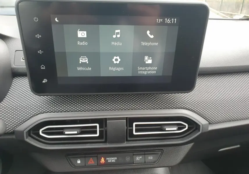 Écran tactile central de la Dacia Sandero 2025 affichant les options radio, média et téléphone, avec aérateurs en dessous.
