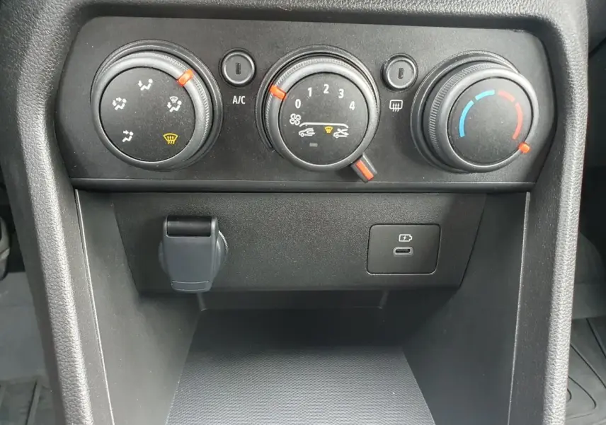 Gros plan sur les commandes de climatisation manuelle et prise USB du tableau de bord d'une Dacia Sandero 2025.