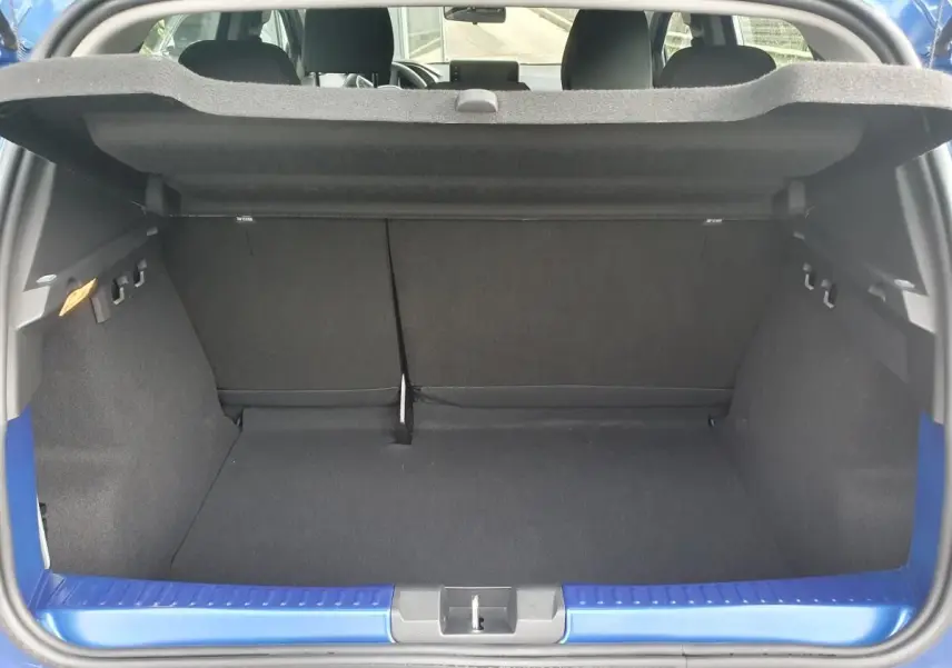 Coffre ouvert vu de l'arrière d'une Dacia Sandero Bleu Iron, montrant l'espace de chargement et la banquette arrière rabattable.
