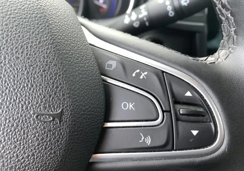Gros plan sur les commandes multifonctions noires du volant cuir du Renault Koleos 2019.