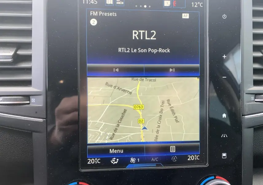 Écran tactile central du Renault Koleos 2019 affichant la navigation et la radio, avec commandes climatisation visibles.