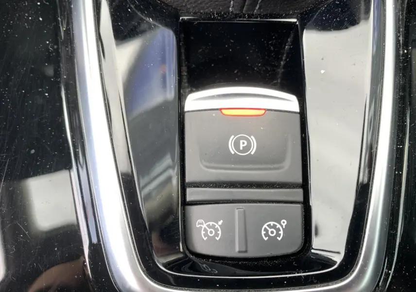 Gros plan sur la console centrale noire brillante du Renault Koleos 2019 avec boutons de frein à main et régulateur de vitesse.