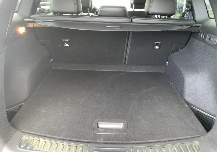 Coffre ouvert vu de l'arrière d'un Renault Koleos 2019 bleu foncé avec banquette arrière et cache-bagages noirs.