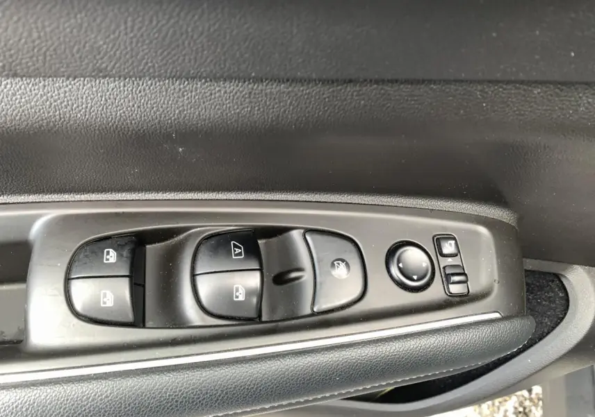 Gros plan sur les commandes de lève-vitres et rétroviseurs côté gauche du Renault Koleos 2019 bleu foncé.