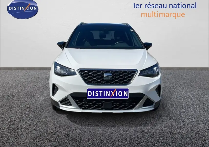 Vue frontale d'un SEAT Arona blanc Nevada avec toit noir, mettant en valeur sa calandre et ses phares LED.
