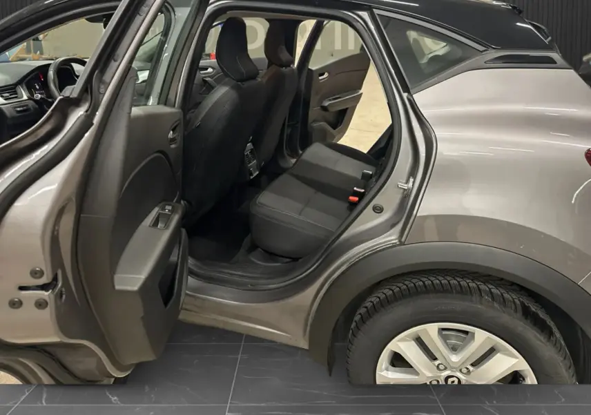 Vue côté gauche arrière du Renault Captur gris foncé avec porte arrière ouverte montrant l’intérieur noir des sièges arrière.