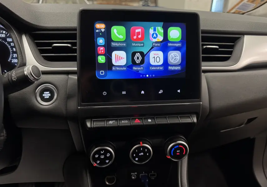 Vue rapprochée du tableau de bord noir du Renault Captur 2021, avec écran tactile central affichant des applications connectées.