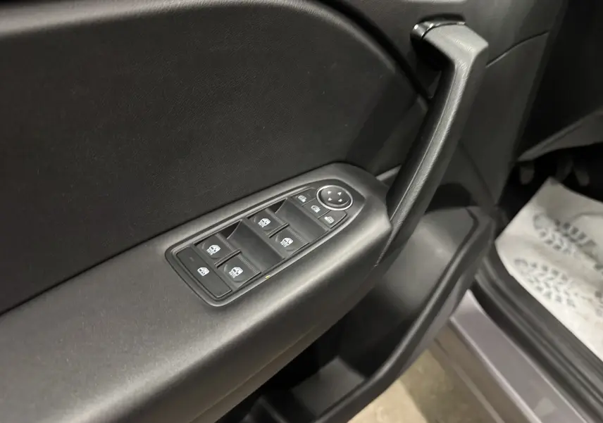 Gros plan sur la commande des vitres électriques côté conducteur d’un Renault Captur gris foncé avec intérieur noir.