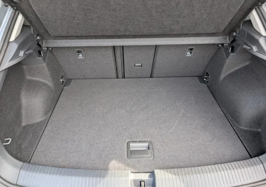 Coffre ouvert vu de l'arrière d'un Volkswagen T-Roc gris, avec plancher plat et revêtement tissu gris.