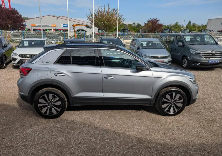 Profil droit d'un Volkswagen T-Roc gris métallisé avec jantes alliage 17 pouces et toit noir, stationné en extérieur.