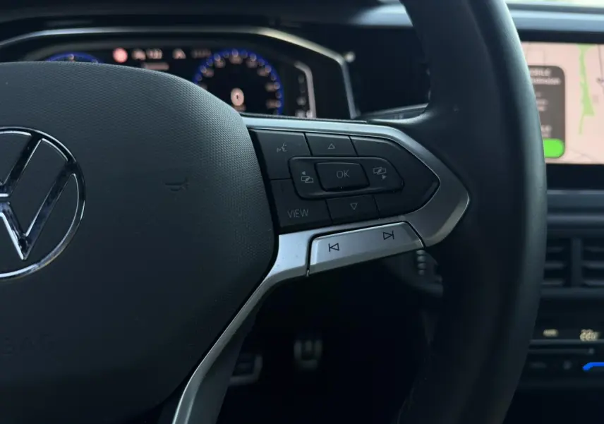 Gros plan sur le volant multifonctions cuir du Volkswagen Taigo TSI 116 DSG R-Line, boutons de commande à droite visibles.