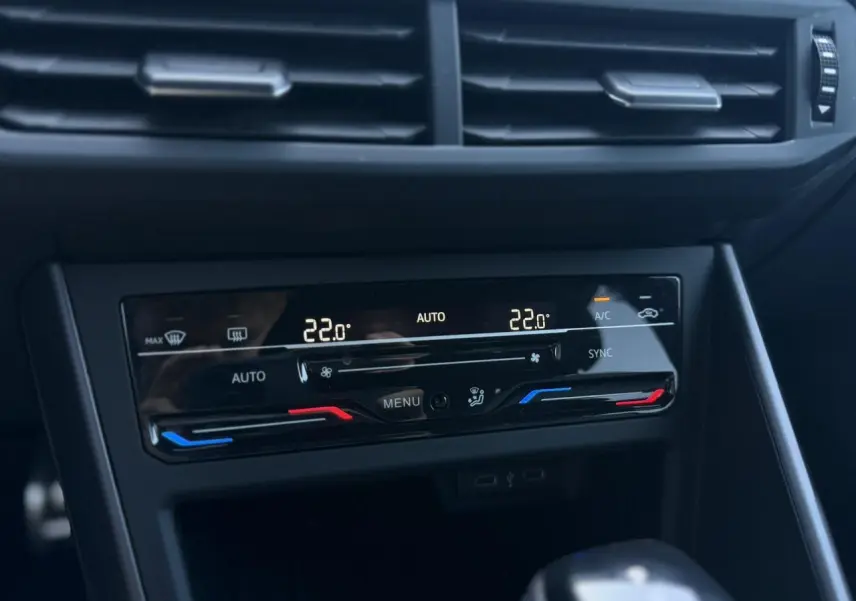 Vue rapprochée de la console centrale du Volkswagen Taigo gris, affichant la climatisation automatique bi-zone à 22°C.