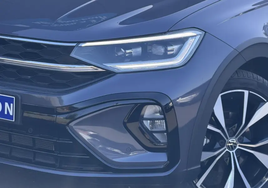 Gros plan sur l'avant droit du Volkswagen Taigo gris intense, mettant en valeur le phare Matrix LED et la jante alliage 18 pouces.