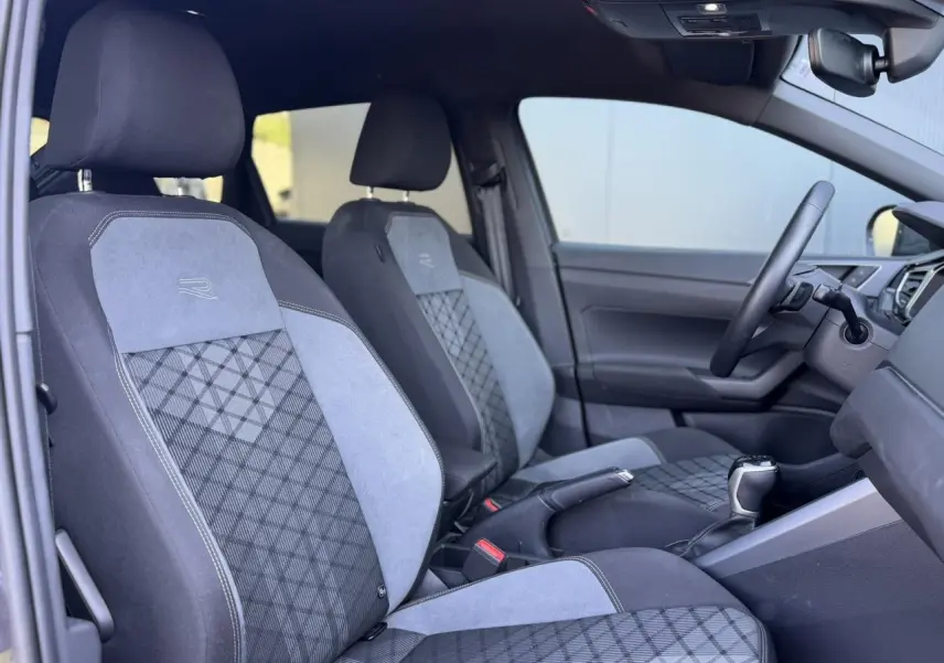 Vue intérieure côté gauche du Volkswagen Taigo R-Line 2025, sièges sport bi-matière gris avec logo R brodé.