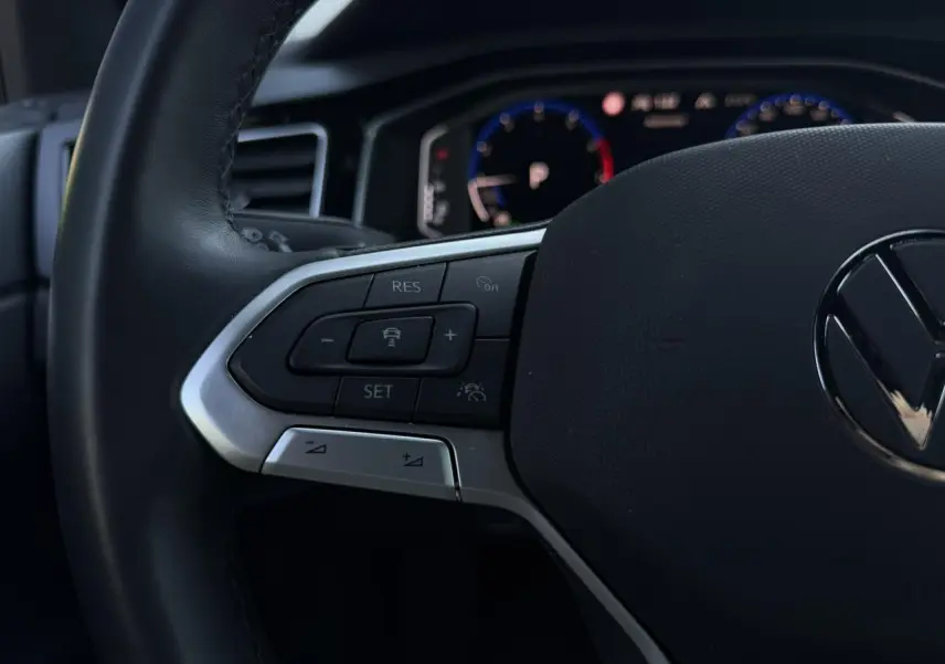 Gros plan sur le volant multifonctions cuir noir du Volkswagen Taigo 2025 avec commandes de régulateur adaptatif.