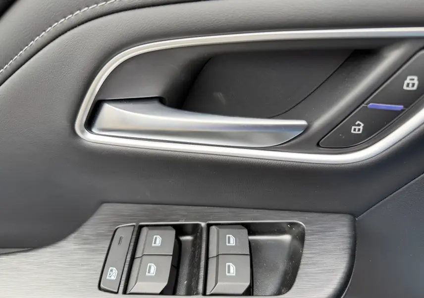 Gros plan sur la poignée intérieure et les commandes des vitres côté conducteur du MG ZS 1.5L HYBRID+ 197CH Luxury en noir.