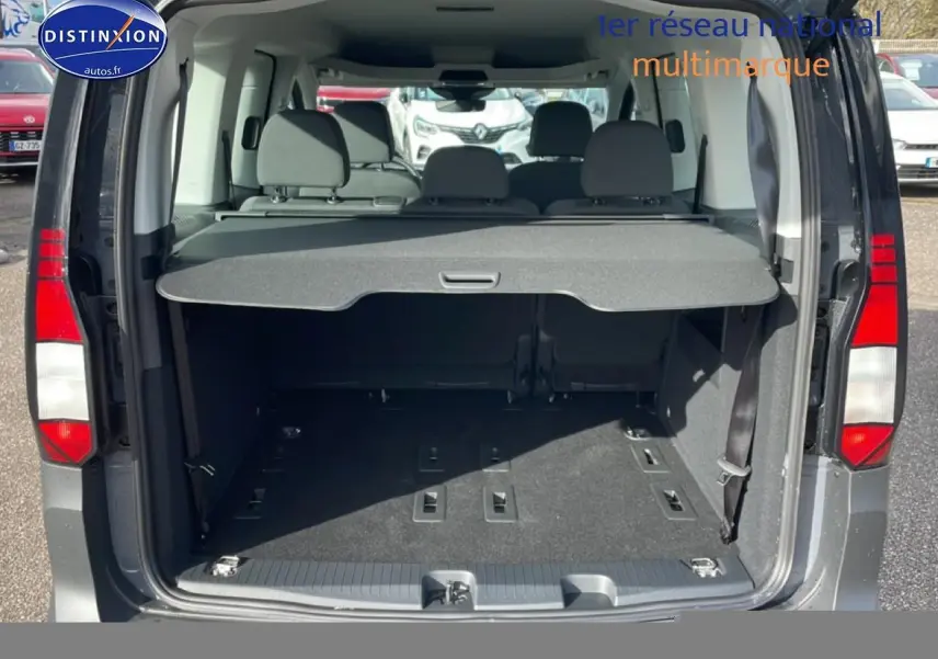 Vue arrière ouverte du Volkswagen Caddy gris pur 2025, montrant le coffre spacieux avec cache-bagages et banquette arrière.