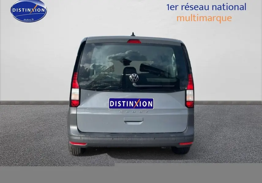 Vue arrière d'un Volkswagen Caddy gris pur 2025 avec vitres teintées et feux verticaux rouges.