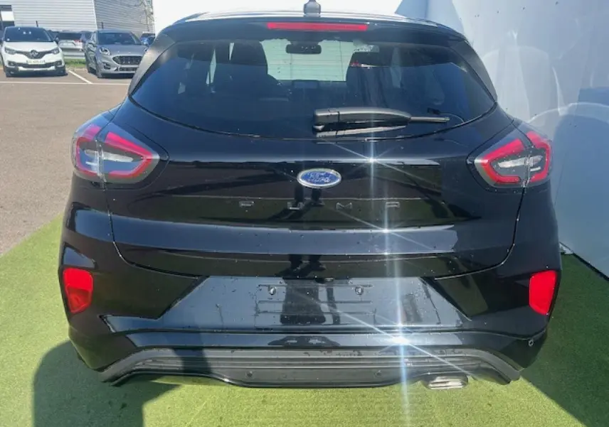 Vue arrière d'un Ford Puma noir Agate 2023 avec feux LED et hayon électrique mains libres visible au soleil.