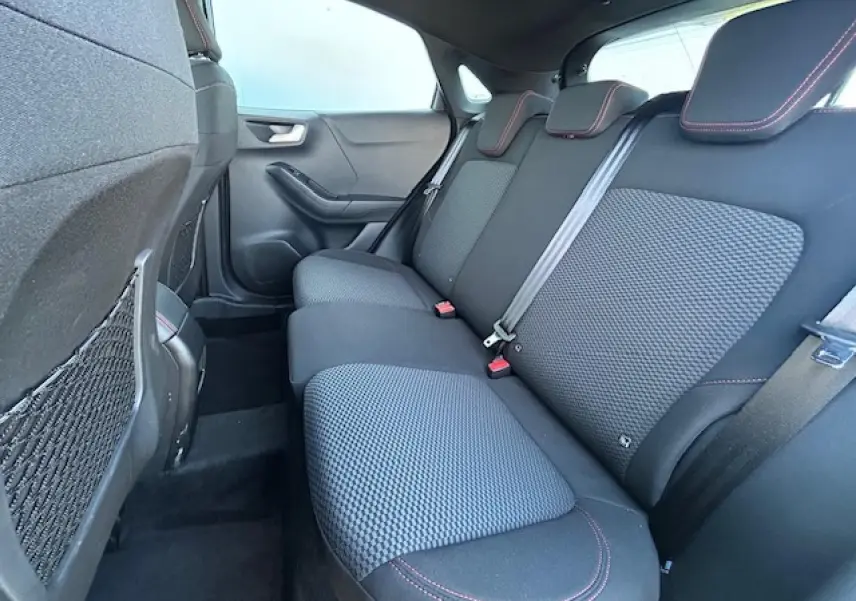 Vue intérieure arrière côté droit du Ford Puma noir agate, banquette tissu noir avec surpiqûres rouges et appuie-têtes intégrés.